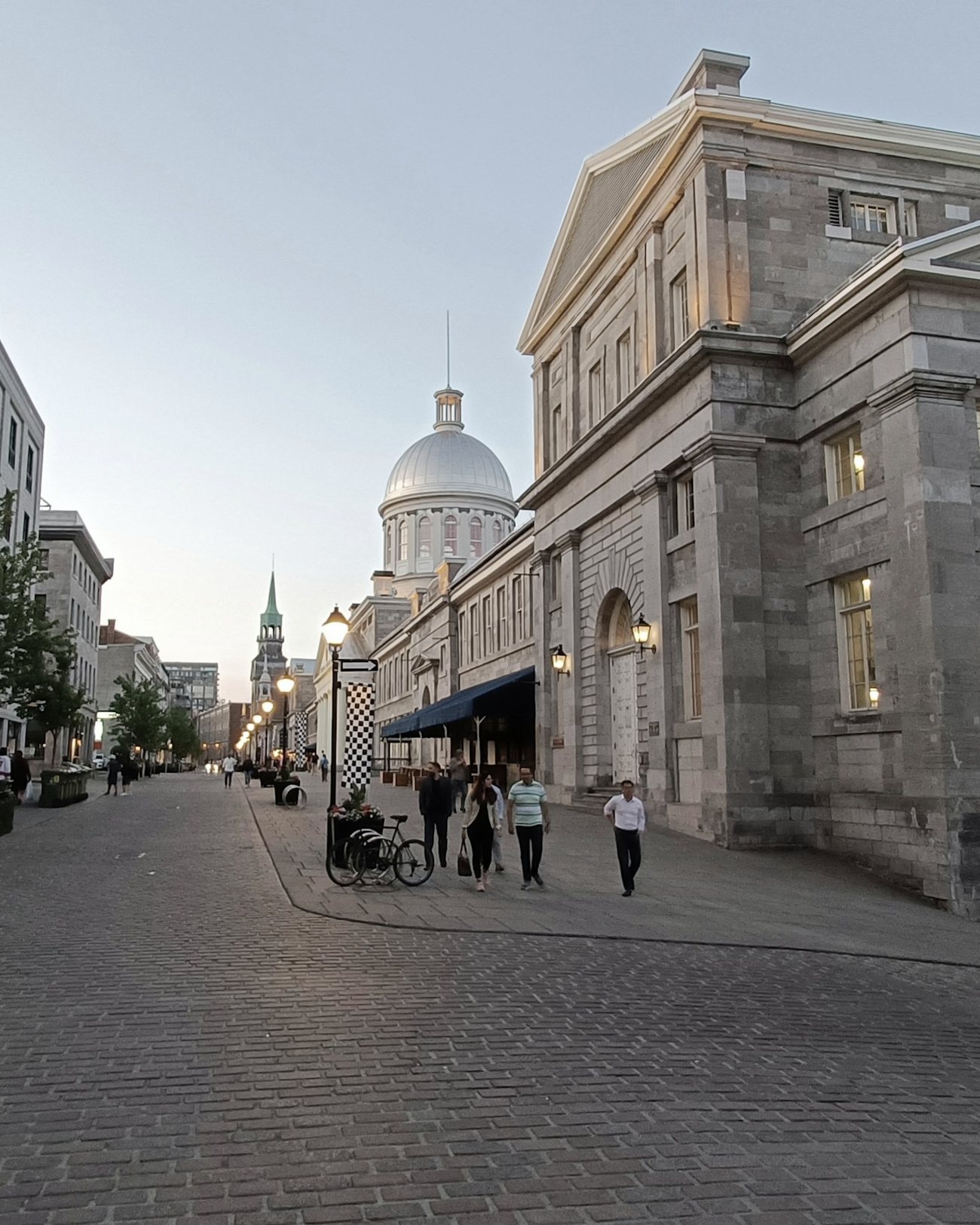 A cobblestone street in Old Montreal at dusk, by the Bonsecours Market
